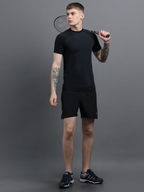 Man in black athletic wear holding a badminton racket against a gray background